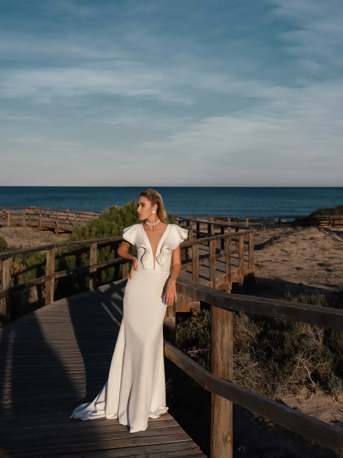 Vestido Marea de JJ Bridal sobre una pasarela de madera junto al mar